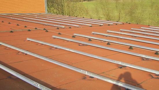 Aluminiumschienen tragen die Photovoltaik
Auf dem Flachdach wurden bisher alle Befestigungspunkte aufgebracht und abgedichtet. Nun werden Profile aus Aluminium aufgeschraubt, die dann die Gestelle für die Aufständerung