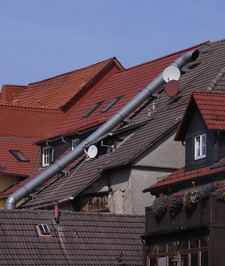 Seltsame Dachlandschaft
Die Dächer auf der Südseite werden für alles Mögliche genutzt. Für Abluft oder Fernsehempfang hat man das Dach schon entdeckt, doch was ist mit Strom und Wärme?