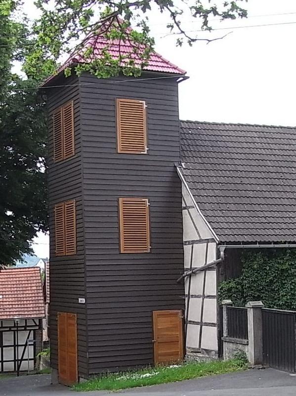 Feuerwehrturm mit Stülpschalung und Lamellen-Läden
Die Lamellen-Läden dienen hier der Belüftung des Turmes. Zum Teil findet man noch Feuerwehrtürme, die eine durchlässige Lattung als Fassade haben.