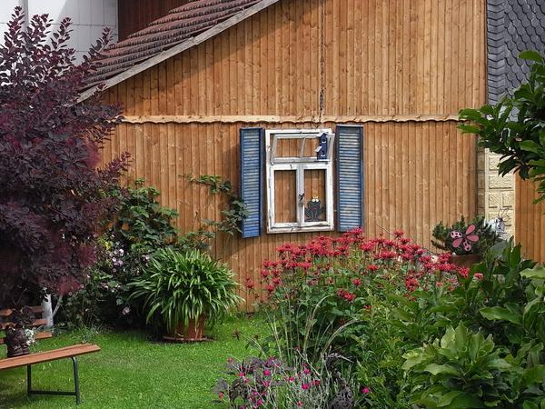 Holzfassade mit altem Fenster verziert
Ein altes Nebengebäude ist schnell mit einer Holzfassade erneuert. Damit die kahle Wand nicht so langweilig aussieht, hat man hier ein altes Fenster mit Fensterläden davorgehängt.