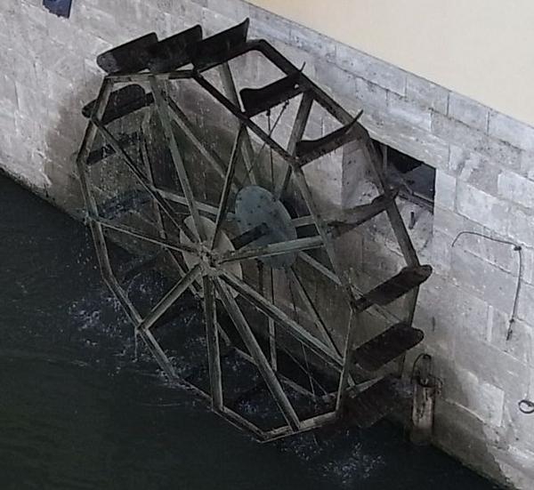 Unterschlächtiges Wasserrad
In starker Strömung muss das Wasser nicht über das Mühlrad laufen, um es anzutreiben. Es wird also auch kein Mühlgraben benötigt, der das Wasser auf einem höheren