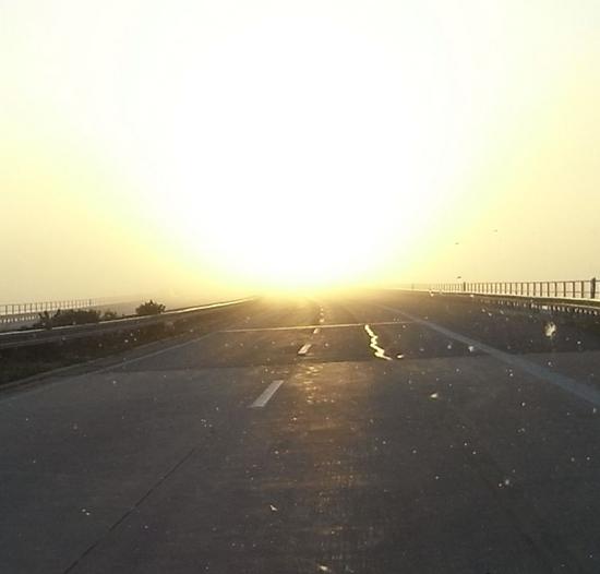 Sonnenaufgang über der Autobahn
Während die Sonne durch den Morgennebel glänzt, hört man überall dieses leise Klickern. Das sind die Geräusche aus den Wechselrichtern der Photovoltaikanlagen.