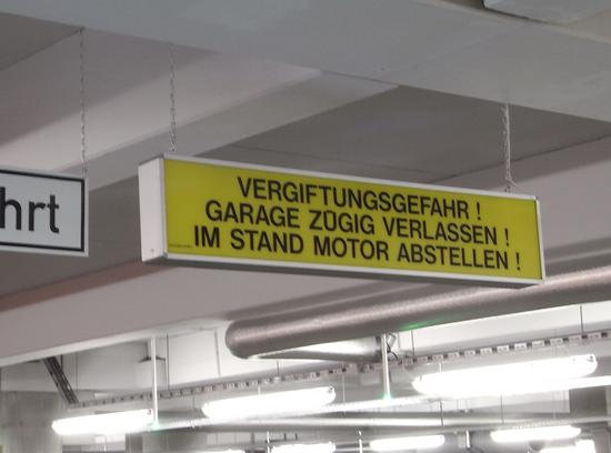 Lebensgefahr im Parkhaus
Ein Hinweisschild im Parkhaus weist auf die Vergiftungsgefahr durch Autoabgase hin. Wie man aus einschlägigen Dramen weiß, sind die Abgase der Autos zum Töten geeignet.