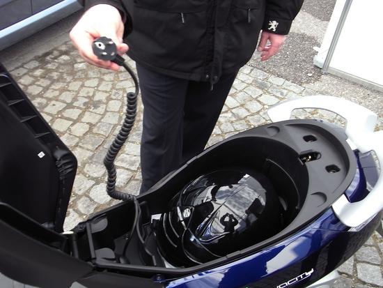 Helmfach im E-Roller
Der Elektroroller von Peugeot hat unter der Sitzbank ein Fach für den Sturzhelm. Das Ladegerät ist ebenfalls über dieses Fach erreichbar.