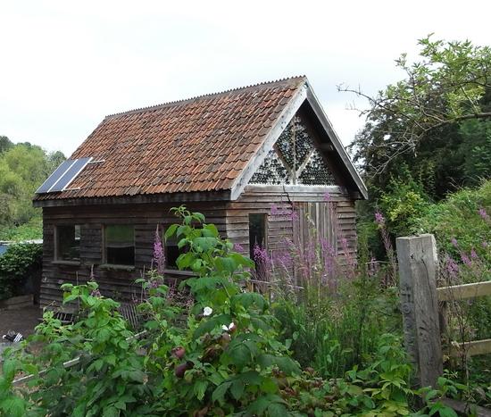 Gemeinschaftshaus im Permakulturgarten
Das Gemeinschaftshaus im Permakulturgarten ist im Fachwerkstil gebaut und außen mit einer Stülpschalung versehen. Die Flaschen im Giebel sind mehr ein gestalterisches Element.