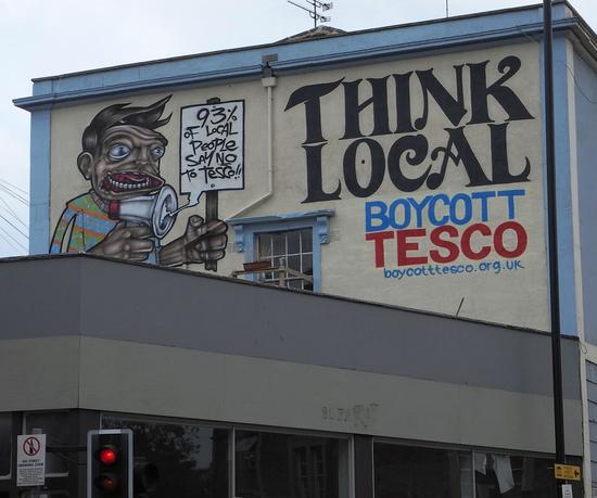 Graffiti gegen Globalisierung
In Bristol sieht man sehr viel Kunst im öffentlichen Raum. Hier ruft ein Künstler auf die Filialen des Tesco-Konzerns zu boykottieren. Tesco breitet sich aus und bedroht die