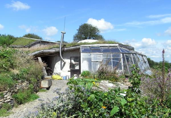 Naturhaus mit integriertem Gewächshaus
Dieses Naturhaus wurde mit der Nordseite in den Hang gebaut. Auf der Südseite ist das Gewächshaus direkt an das Haus angebaut. Es dient als zusätzlicher Wärmepuffer.