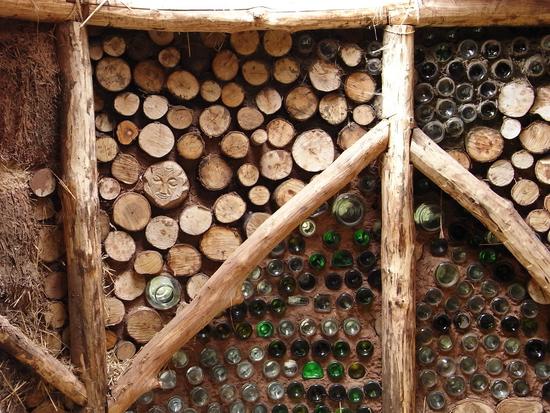 Baustoff Altglas
Im Gemeinschaftshaus aus Holz und Lehm haben die Probanden hier eine Wand mit alten Flaschen verziert. Die Flaschen liegen in Lehm eingebettet, so dass ein wenig Licht