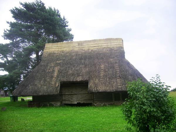 Blockhaus mit Schilfdach
Diese Scheune ist ein klassisches Beispiel für Bauen mit regional verfügbaren Naturbaustoffen. Das Fundament aus Naturstein, die Wände aus Holz und das Dach mit Schilf gedeckt.