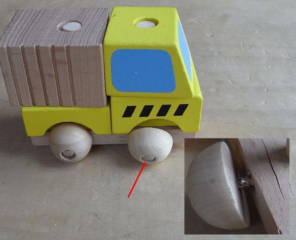 Qualitätsmangel am Holzspielzeug
Das zweite Holzauto vom gleichen Hersteller offenbart den nächsten Qualitätsmangel, der wiederum zum Sicherheitsrisiko werden kann. Die Räder vom Spielzeugauto sind mit Schrauben